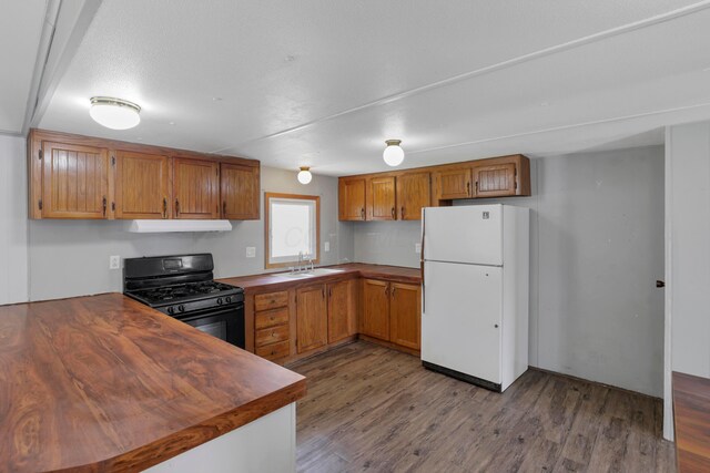264 Timberline Dr, Circleville, OH 43113 - kitchen featuring freestanding refrigerator, black gas stove, range hood, brown cabinets, and dark wood-type flooring