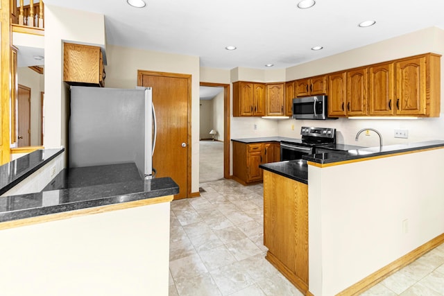 4775 Saint Andrews Dr, Westerville, OH 43082 - kitchen with appliances with stainless steel finishes, a peninsula, brown cabinetry, recessed lighting, and dark stone counters