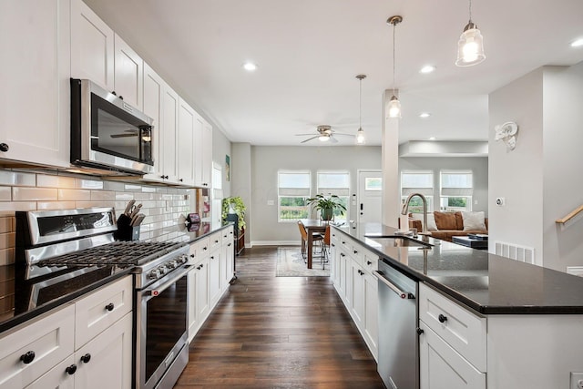 1366 Cole St, Columbus, OH 43205 - kitchen with stainless steel appliances, ceiling fan, decorative backsplash, dark wood-style floors, and a kitchen island with sink