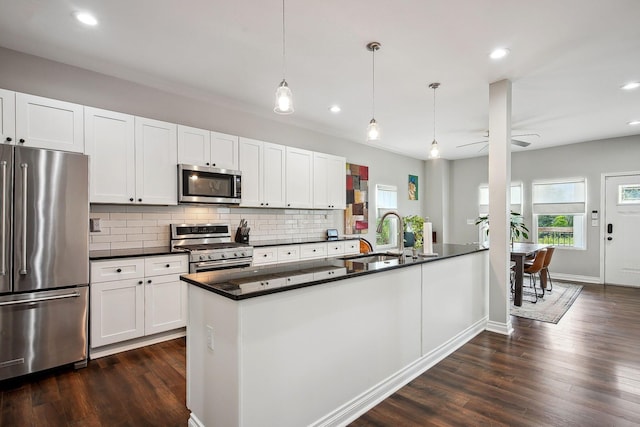 1366 Cole St, Columbus, OH 43205 - kitchen with stainless steel appliances, dark countertops, backsplash, dark wood-style floors, and decorative light fixtures