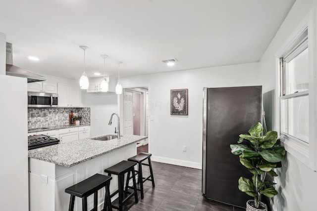 4425 Saint Ann Ln, Columbus, OH 43213 - kitchen featuring appliances with stainless steel finishes, white cabinets, decorative backsplash, a breakfast bar area, and light stone counters
