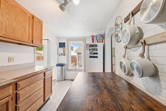 67 W Columbus St, Mount Sterling, OH 43143 - kitchen featuring light wood finished floors, a textured ceiling, arched walkways, and light countertops