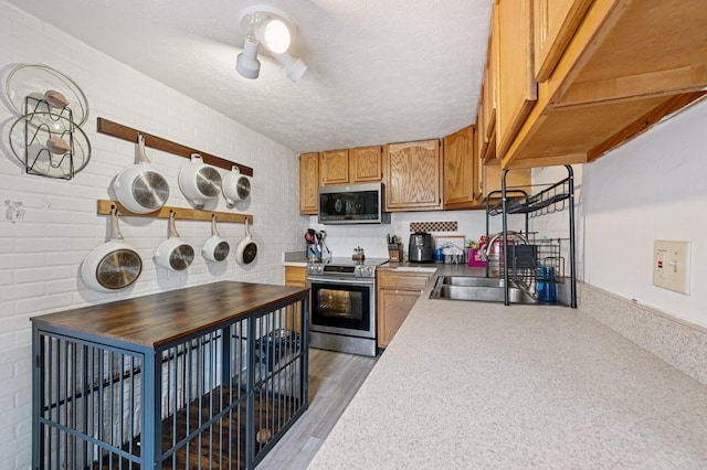 67 W Columbus St, Mount Sterling, OH 43143 - kitchen featuring appliances with stainless steel finishes, a textured ceiling, light countertops, brown cabinetry, and wood finished floors