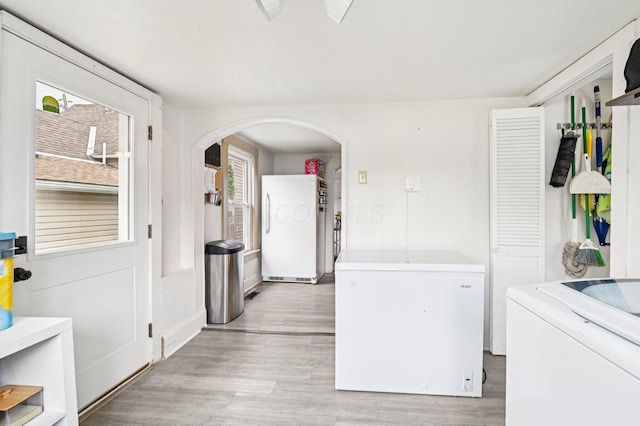 67 W Columbus St, Mount Sterling, OH 43143 - kitchen with fridge, arched walkways, washing machine and clothes dryer, and light wood-style flooring