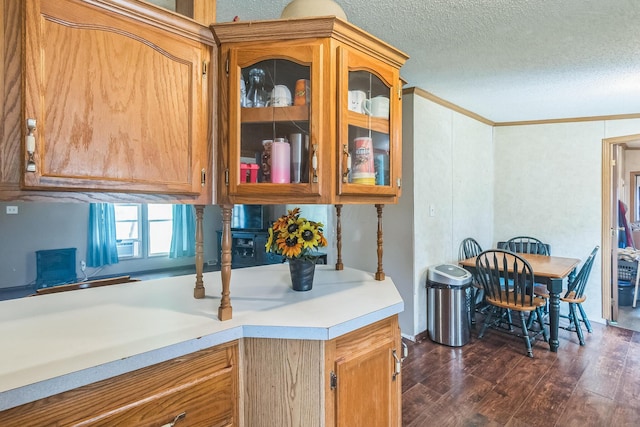 1609 Foraker Ave, Findlay, OH 45840 - kitchen featuring dark wood finished floors, light countertops, glass insert cabinets, crown molding, and a textured ceiling