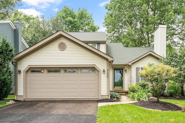 8135 Barlow Rd, Westerville, OH 43081 - view of front of property with asphalt driveway, an attached garage, roof with shingles, and a chimney