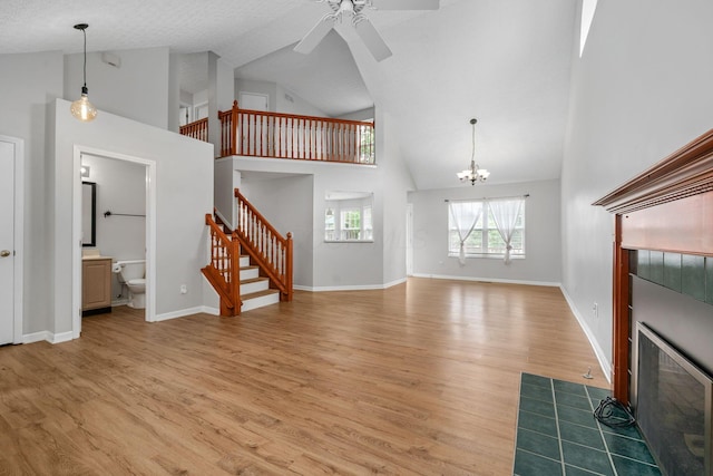 8135 Barlow Rd, Westerville, OH 43081 - unfurnished living room featuring high vaulted ceiling, stairway, a ceiling fan, light wood-style floors, and a fireplace