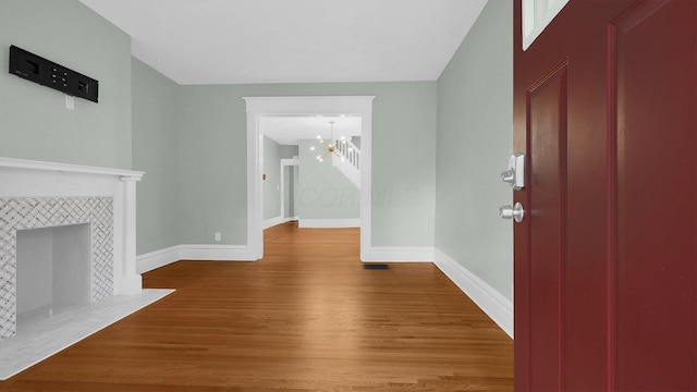 737 Wilson Ave, Columbus, OH 43205 - unfurnished living room with a chandelier, wood finished floors, and a tiled fireplace