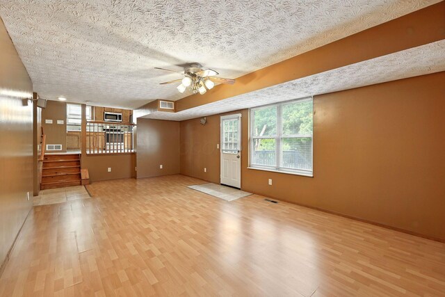 3576 Blendon Bend Way, Columbus, OH 43231 - unfurnished living room with light wood-style flooring, a textured ceiling, a ceiling fan, healthy amount of natural light, and stairway