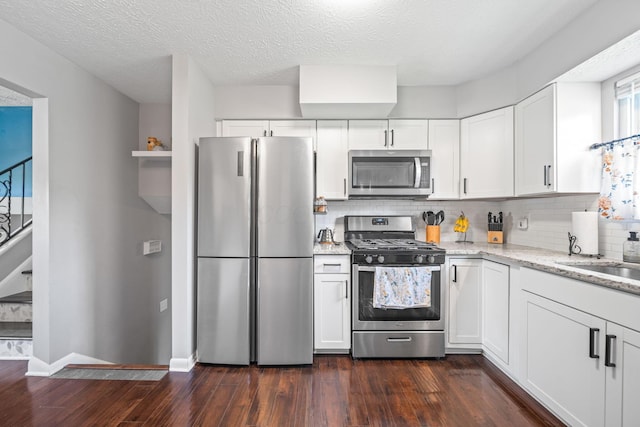 3221 E Hudson St, Columbus, OH 43219 - kitchen featuring stainless steel appliances, dark wood-type flooring, tasteful backsplash, light stone counters, and white cabinets