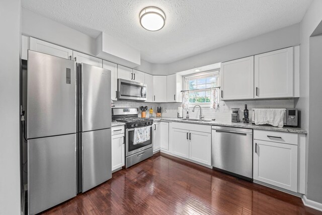 3221 E Hudson St, Columbus, OH 43219 - kitchen with stainless steel appliances, backsplash, light stone countertops, a textured ceiling, and dark wood finished floors