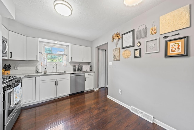 3221 E Hudson St, Columbus, OH 43219 - kitchen with appliances with stainless steel finishes, backsplash, dark wood finished floors, a textured ceiling, and white cabinetry