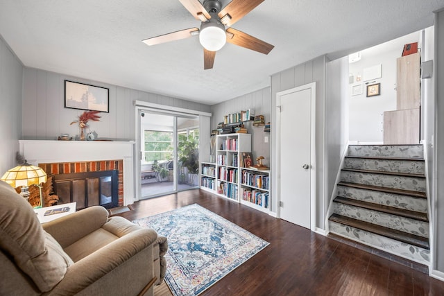 3221 E Hudson St, Columbus, OH 43219 - living room featuring ceiling fan, wood finished floors, a brick fireplace, stairs, and a textured ceiling
