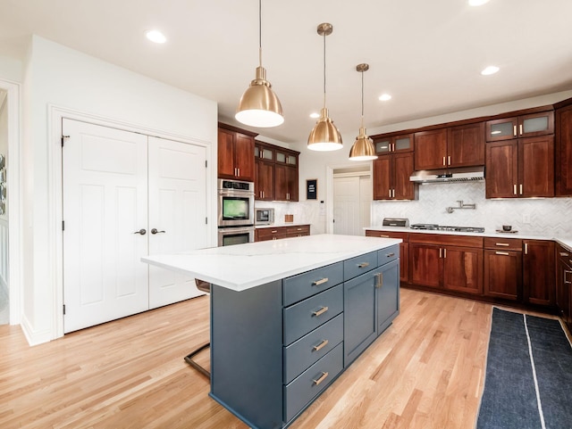 5808 Glendavon Loop, Dublin, OH 43016 - kitchen featuring appliances with stainless steel finishes, under cabinet range hood, light wood-style floors, a center island, and backsplash