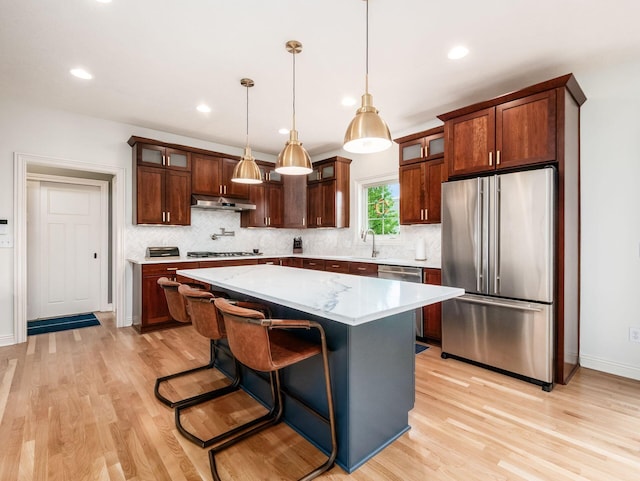 5808 Glendavon Loop, Dublin, OH 43016 - kitchen with appliances with stainless steel finishes, light wood-type flooring, under cabinet range hood, decorative backsplash, and recessed lighting