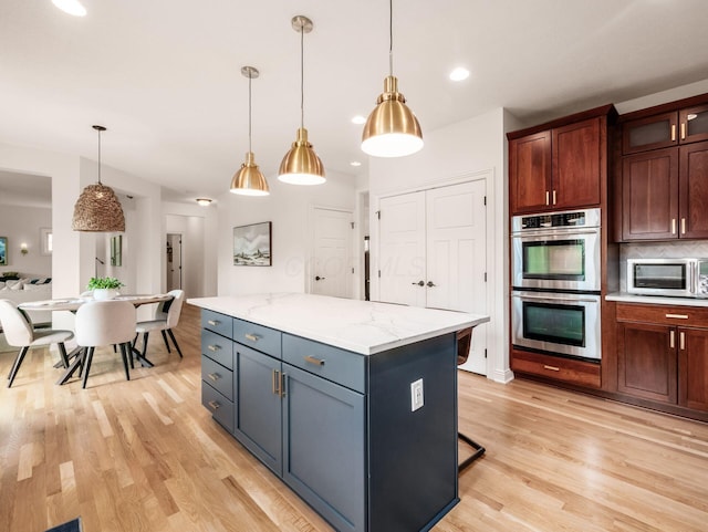 5808 Glendavon Loop, Dublin, OH 43016 - kitchen with appliances with stainless steel finishes, light wood-style floors, pendant lighting, a center island, and backsplash