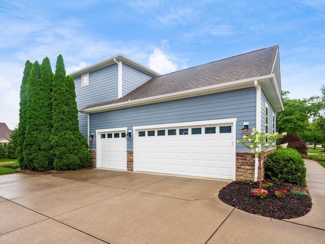 5808 Glendavon Loop, Dublin, OH 43016 - view of property exterior featuring stone siding, concrete driveway, a garage, and roof with shingles