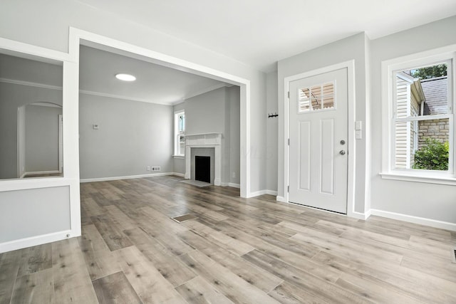 1693 Bide A Wee Park Ave, Columbus, OH 43205 - unfurnished living room with light wood-style floors, a fireplace with flush hearth, and arched walkways