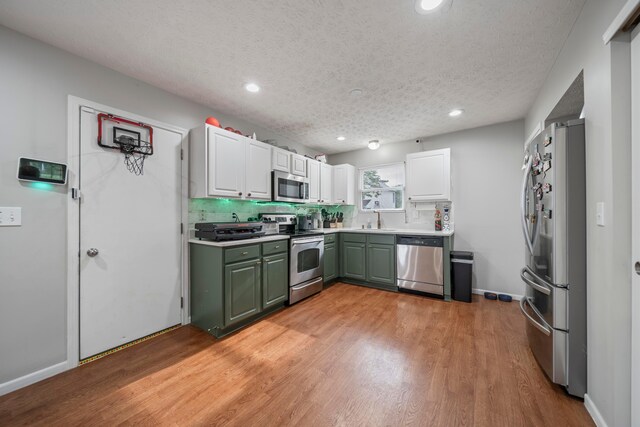 2986 E Powell Rd, Columbus, OH 43240 - kitchen with appliances with stainless steel finishes, green cabinetry, recessed lighting, white cabinetry, and light wood-style flooring