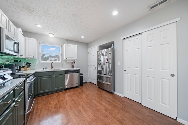 2986 E Powell Rd, Columbus, OH 43240 - kitchen with stainless steel appliances, white cabinetry, wood finished floors, recessed lighting, and light countertops