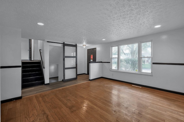4974 Silverton Dr, Columbus, OH 43232 - unfurnished living room with a barn door, a textured ceiling, hardwood / wood-style flooring, and recessed lighting