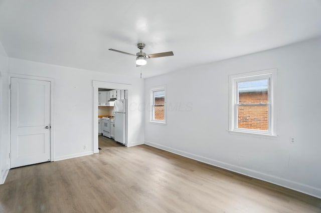 2678 Eakin Rd, Columbus, OH 43204 - unfurnished bedroom with freestanding refrigerator, wood finished floors, multiple windows, and ceiling fan