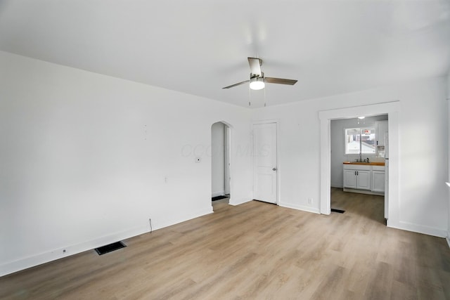 2678 Eakin Rd, Columbus, OH 43204 - unfurnished bedroom featuring light wood finished floors, arched walkways, ensuite bathroom, and ceiling fan