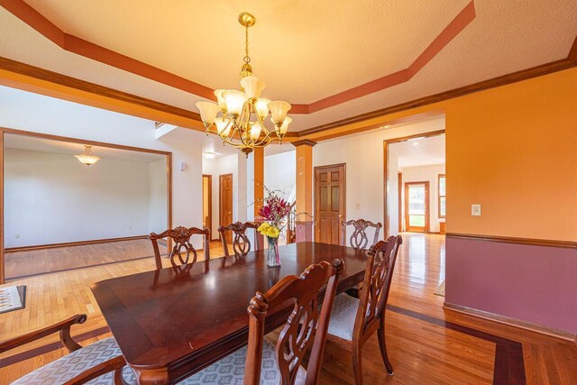 8510 Morgan St, Pickerington, OH 43147 - dining area with a chandelier, wood finished floors, a raised ceiling, ornate columns, and crown molding