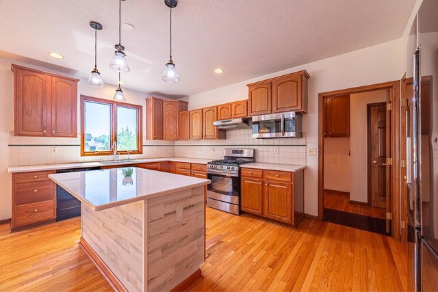8510 Morgan St, Pickerington, OH 43147 - kitchen with appliances with stainless steel finishes, light countertops, light wood-type flooring, decorative backsplash, and hanging light fixtures