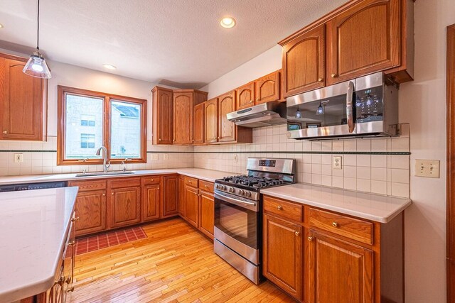 8510 Morgan St, Pickerington, OH 43147 - kitchen featuring stainless steel appliances, under cabinet range hood, light wood-style flooring, brown cabinets, and light countertops