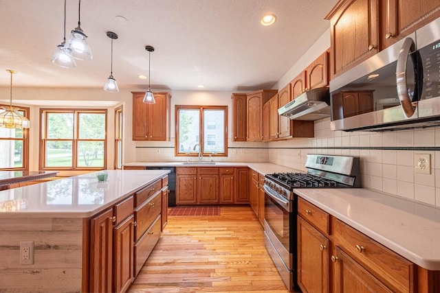 8510 Morgan St, Pickerington, OH 43147 - kitchen featuring stainless steel appliances, under cabinet range hood, light wood finished floors, brown cabinets, and light countertops
