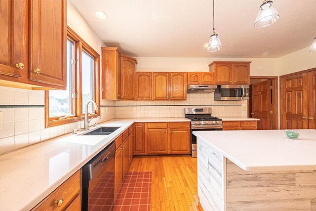 8510 Morgan St, Pickerington, OH 43147 - kitchen featuring appliances with stainless steel finishes, light countertops, light wood-type flooring, under cabinet range hood, and brown cabinetry