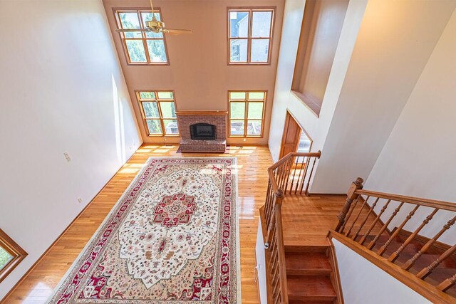 8510 Morgan St, Pickerington, OH 43147 - living area with wood finished floors, a towering ceiling, a brick fireplace, a ceiling fan, and stairs
