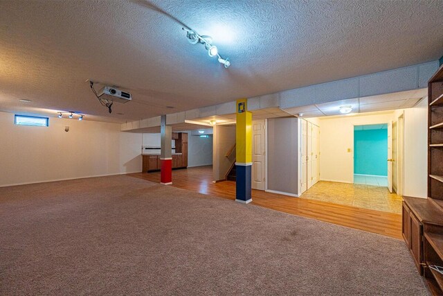 8510 Morgan St, Pickerington, OH 43147 - below grade area featuring a textured ceiling, carpet flooring, rail lighting, stairs, and wood finished floors