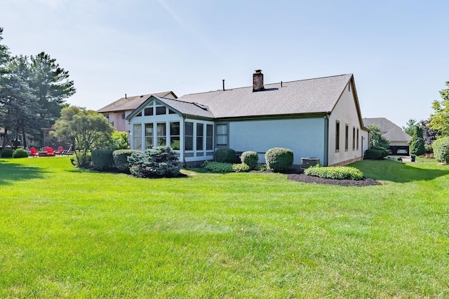 5608 Lynx Dr, Westerville, OH 43081 - rear view of house with a chimney, a lawn, stucco siding, a shingled roof, and a sunroom