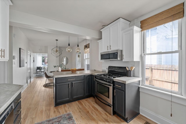 442 Thurman Ave, Columbus, OH 43206 - kitchen featuring stainless steel appliances, a peninsula, light countertops, white cabinetry, and plenty of natural light
