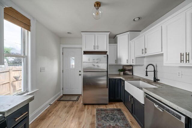 442 Thurman Ave, Columbus, OH 43206 - kitchen featuring stainless steel appliances, white cabinetry, light wood-style flooring, light countertops, and backsplash