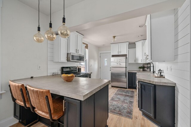 442 Thurman Ave, Columbus, OH 43206 - kitchen featuring appliances with stainless steel finishes, light wood-type flooring, a peninsula, white cabinetry, and a kitchen bar