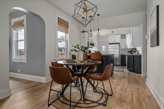 442 Thurman Ave, Columbus, OH 43206 - dining room featuring arched walkways, light wood-style flooring, and a chandelier