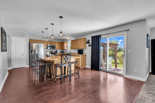 1626 Geranium Dr, Lewis Center, OH 43035 - kitchen featuring stainless steel appliances, light countertops, dark wood-style flooring, a textured ceiling, and a breakfast bar
