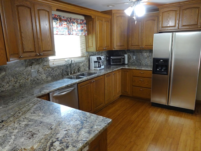 1766 Thrailkill Rd, Grove City, OH 43123 - kitchen with stainless steel appliances, brown cabinetry, light stone countertops, decorative backsplash, and a ceiling fan