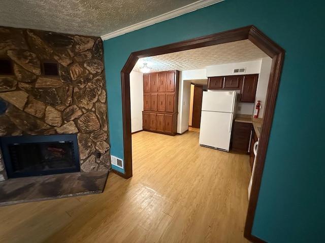 5600 Cartwright Ln Unit 19, Columbus, OH 43231 - unfurnished living room featuring a textured ceiling, light wood-style floors, crown molding, and a stone fireplace