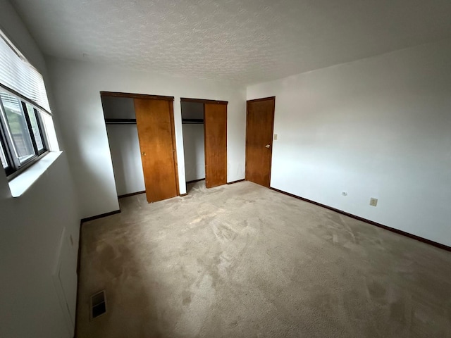 5600 Cartwright Ln Unit 19, Columbus, OH 43231 - unfurnished bedroom with multiple closets, light carpet, and a textured ceiling