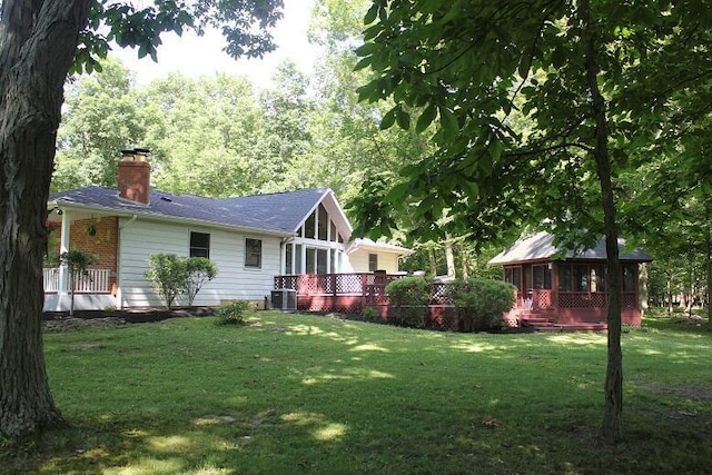 6781 Thoreau Ln NE, Baltimore, OH 43105 - view of side of home with a sunroom, a chimney, a lawn, and a deck