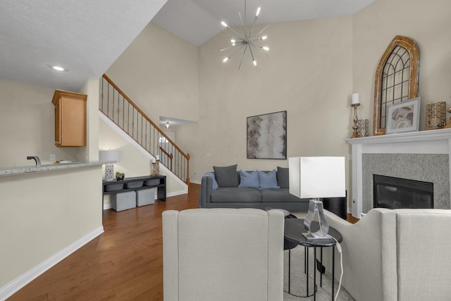 6277 Hudson Reserve Way, Westerville, OH 43081 - living room with wood finished floors, stairs, a chandelier, high vaulted ceiling, and a high end fireplace