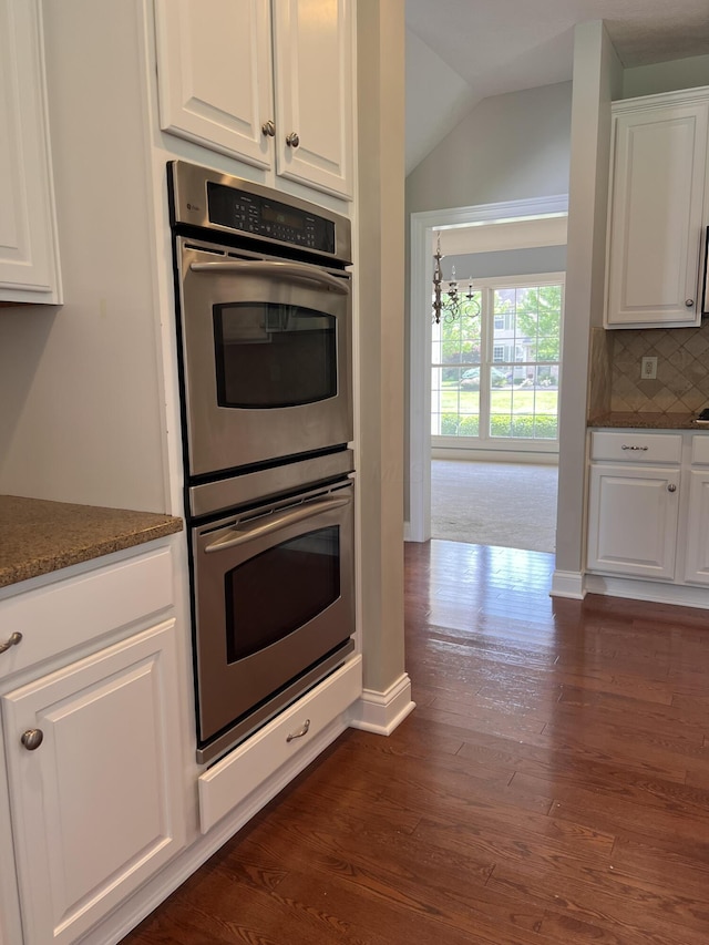 8730 Swisher Creek Xing, New Albany, OH 43054 - kitchen featuring double oven, white cabinetry, dark wood-style flooring, lofted ceiling, and decorative backsplash