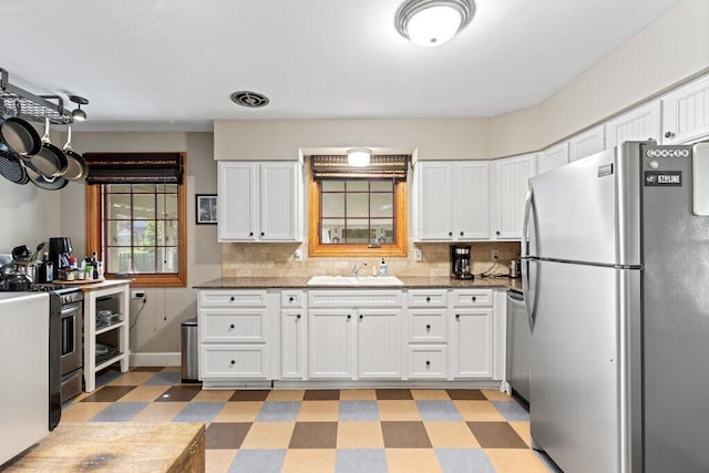 1855 Suffolk Rd, Columbus, OH 43221 - kitchen with appliances with stainless steel finishes, light floors, white cabinetry, and tasteful backsplash