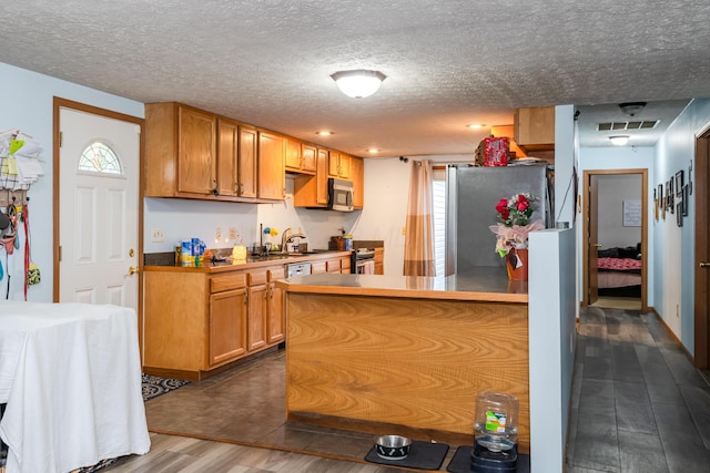508 Carolyn Rd, Washington Court House, OH 43160 - kitchen featuring stainless steel appliances, dark wood-style floors, a textured ceiling, and brown cabinets