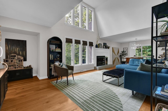 160 Wildwood Dr, Granville, OH 43023 - living area with high vaulted ceiling, a chandelier, light wood-style floors, and a fireplace with raised hearth