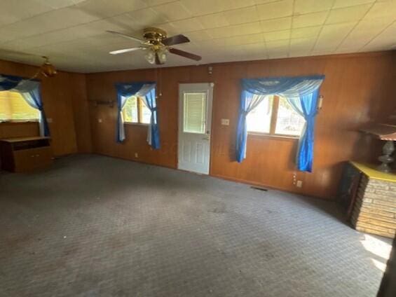 498 E Mark St, Marion, OH 43302 - unfurnished living room featuring wood walls, carpet, and a ceiling fan